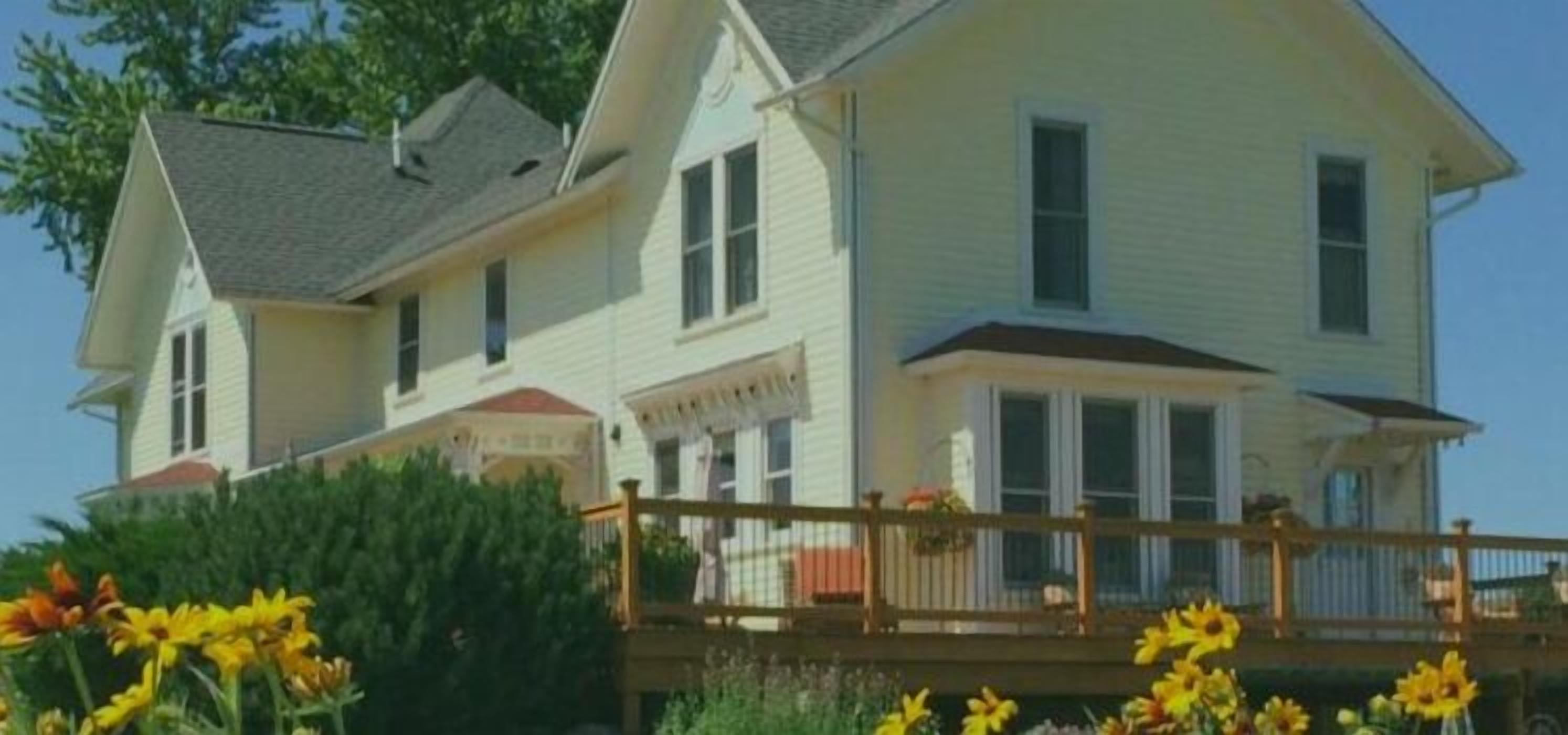 A two-story house with a porch and a wooden deck.