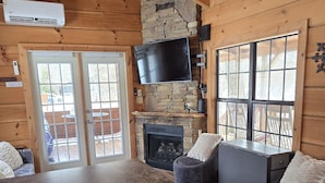 A wooden cabin interior with a kitchen, dining area, and fireplace. - Linville River Log Cabins (Newland)