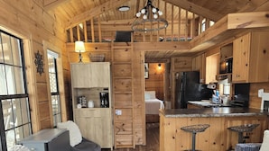 A cozy cabin interior with a kitchen, dining area, and two seating areas. - Linville River Log Cabins (Newland)