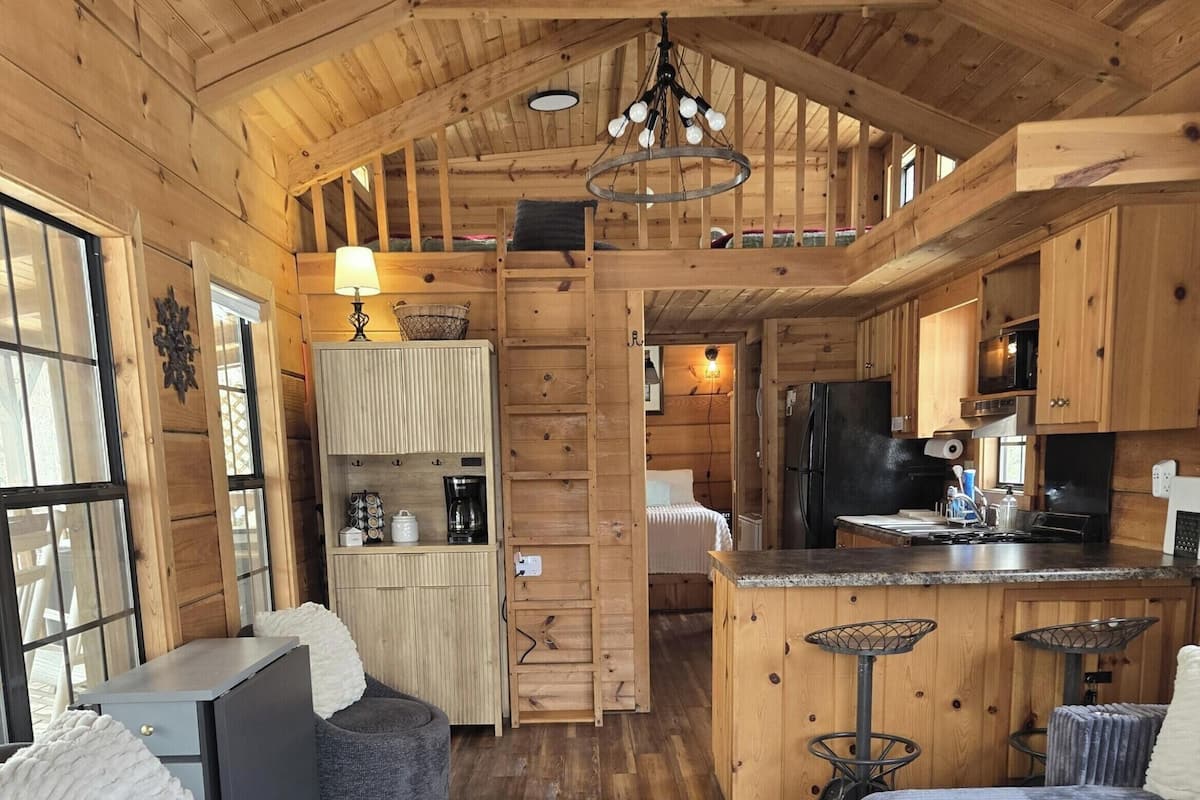 A cozy cabin interior with a kitchen, dining area, and two seating areas.