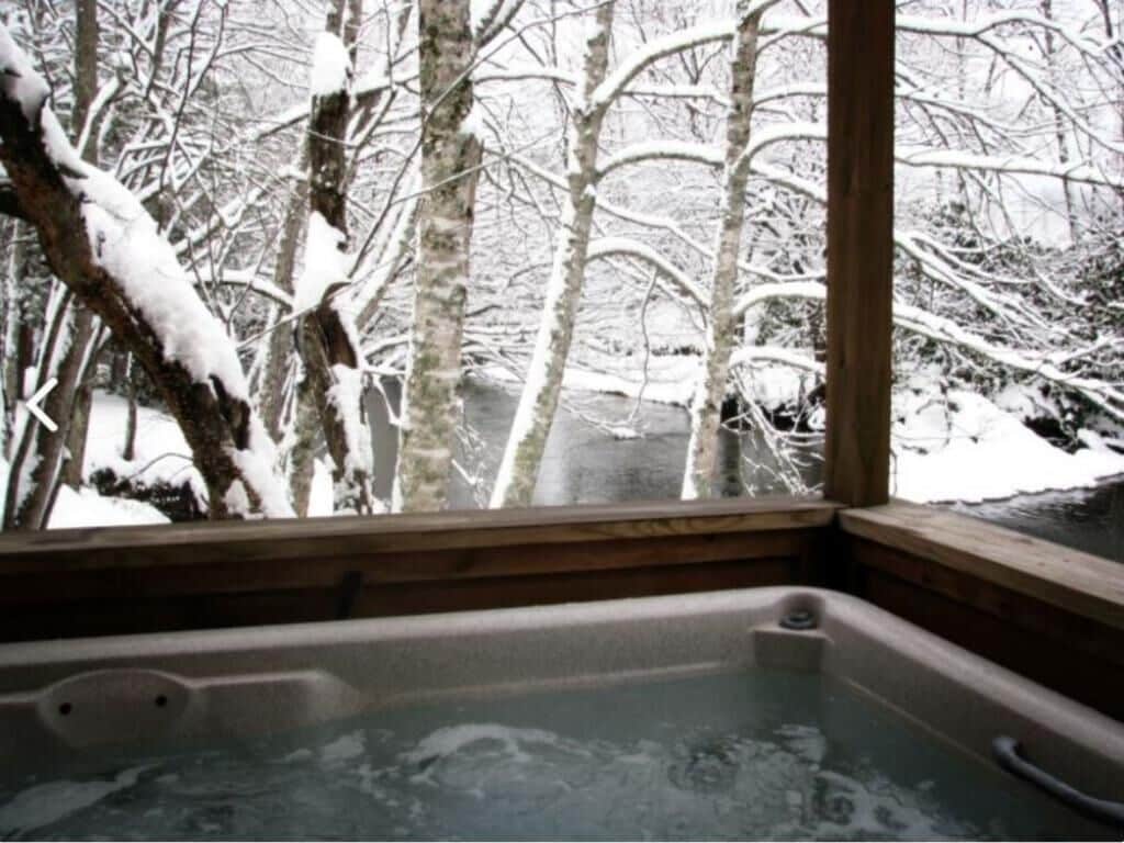 Ein Whirlpool mit Blick auf schneebedeckte Bäume.