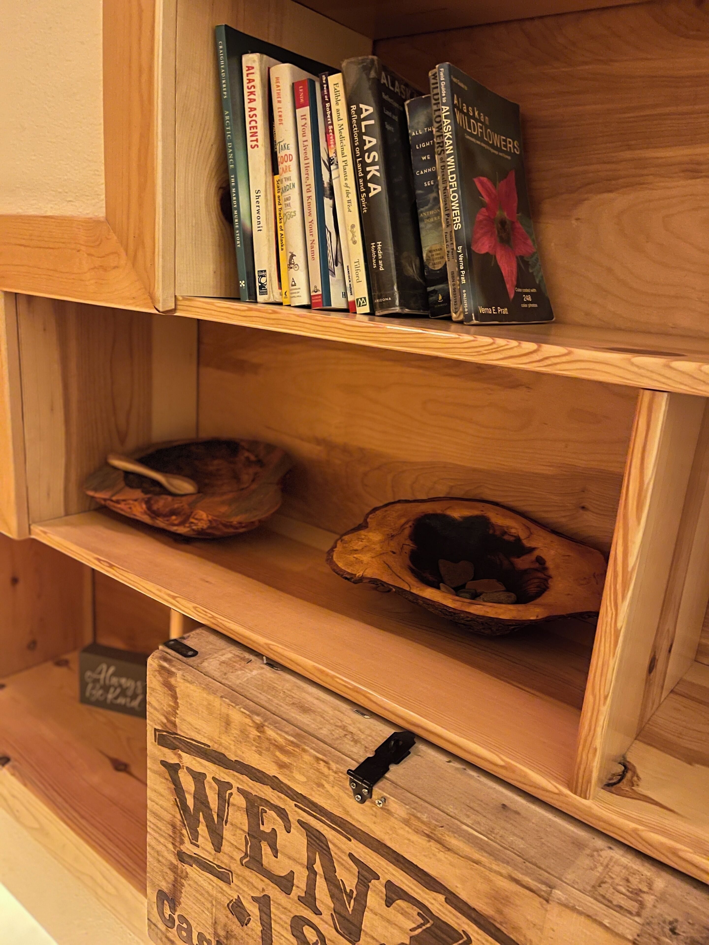 Ein Holzboden mit Büchern und einer geschnitzten Holzkiste mit dem Schriftzug 'WEN 1913'.