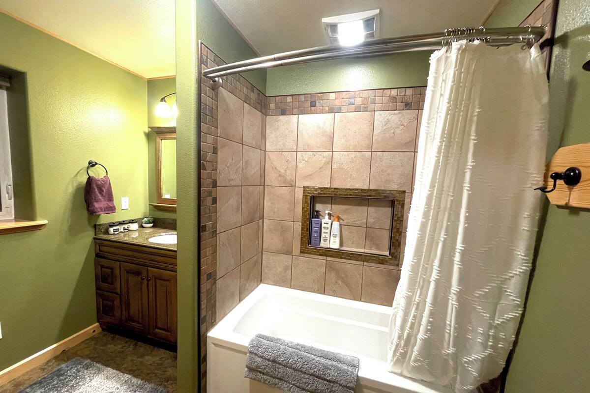 Un baño con ducha, bañera y tocador con espejo.