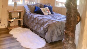Een gezellige slaapkamer met een groot bed, een krabpaal en een rustieke decoratie van een boomstam.