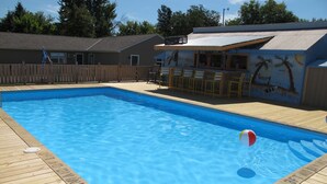 Une piscine rectangulaire entourée d’une terrasse en bois.