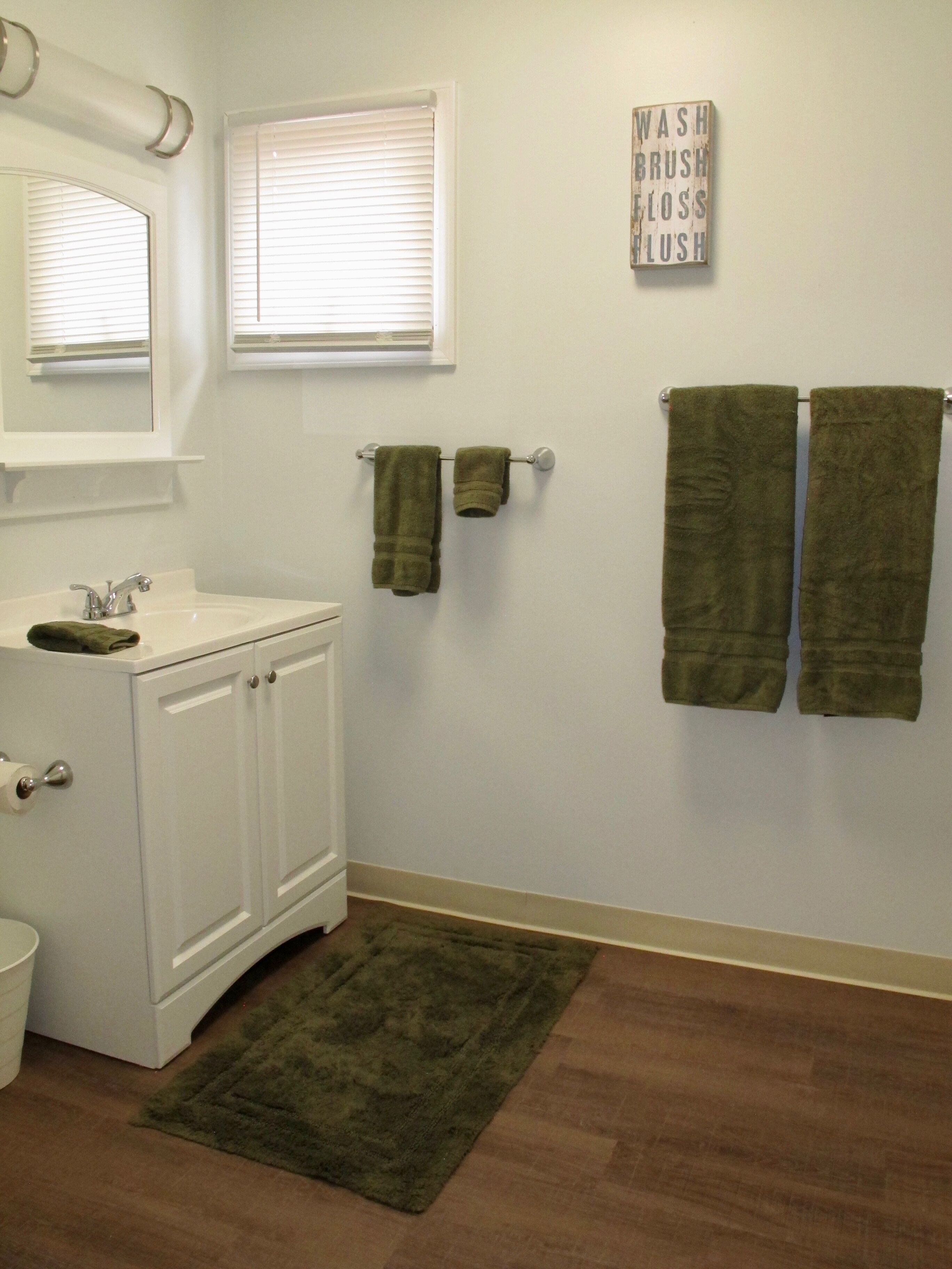 A bathroom with a white sink, mirror, and two towels hanging on a towel rack.