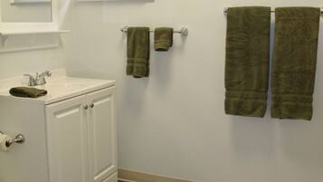 A bathroom with a white sink, mirror, and two towels hanging on a towel rack.