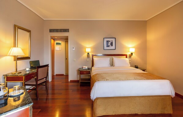Une chambre d’hôtel équipée d’un lit, d’un bureau, d’une chaise et de lampes de chevet.