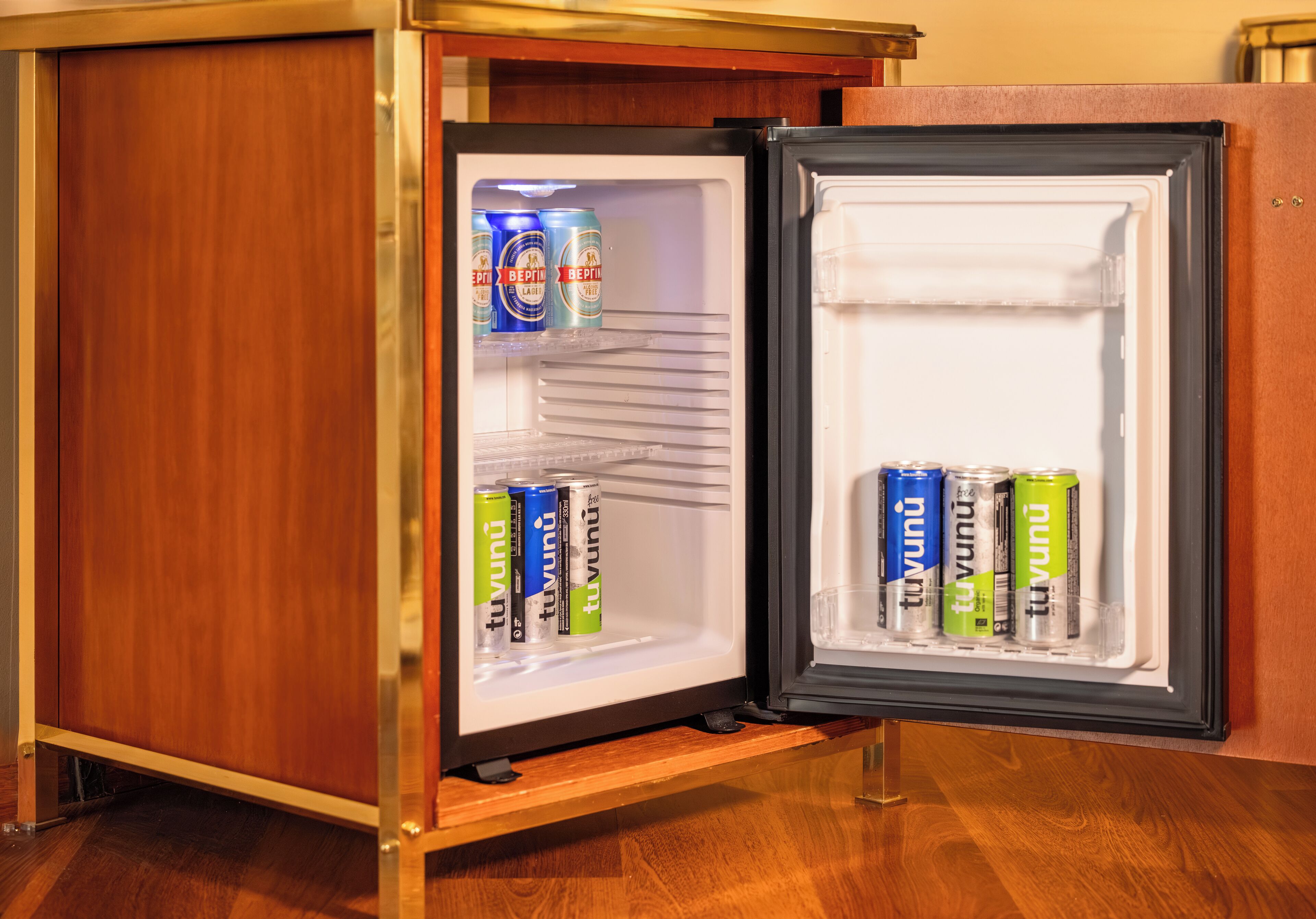 Ein Minikühlschrank mit zwei Ablagen, auf denen sich mehrere Getränkedosen befinden.