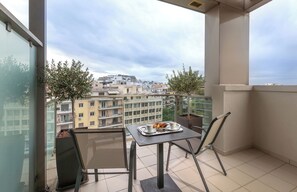 Un balcon avec une table dressée pour deux personnes, offrant une vue sur le paysage urbain.