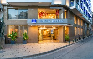 L’extérieur de l’hôtel Ilisia se distingue par sa façade moderne, ses grandes fenêtres et son entrée accueillante.