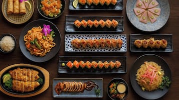 Variedad de platos que incluyen sushi, sashimi y tazones de arroz, presentados en múltiples fuentes.
