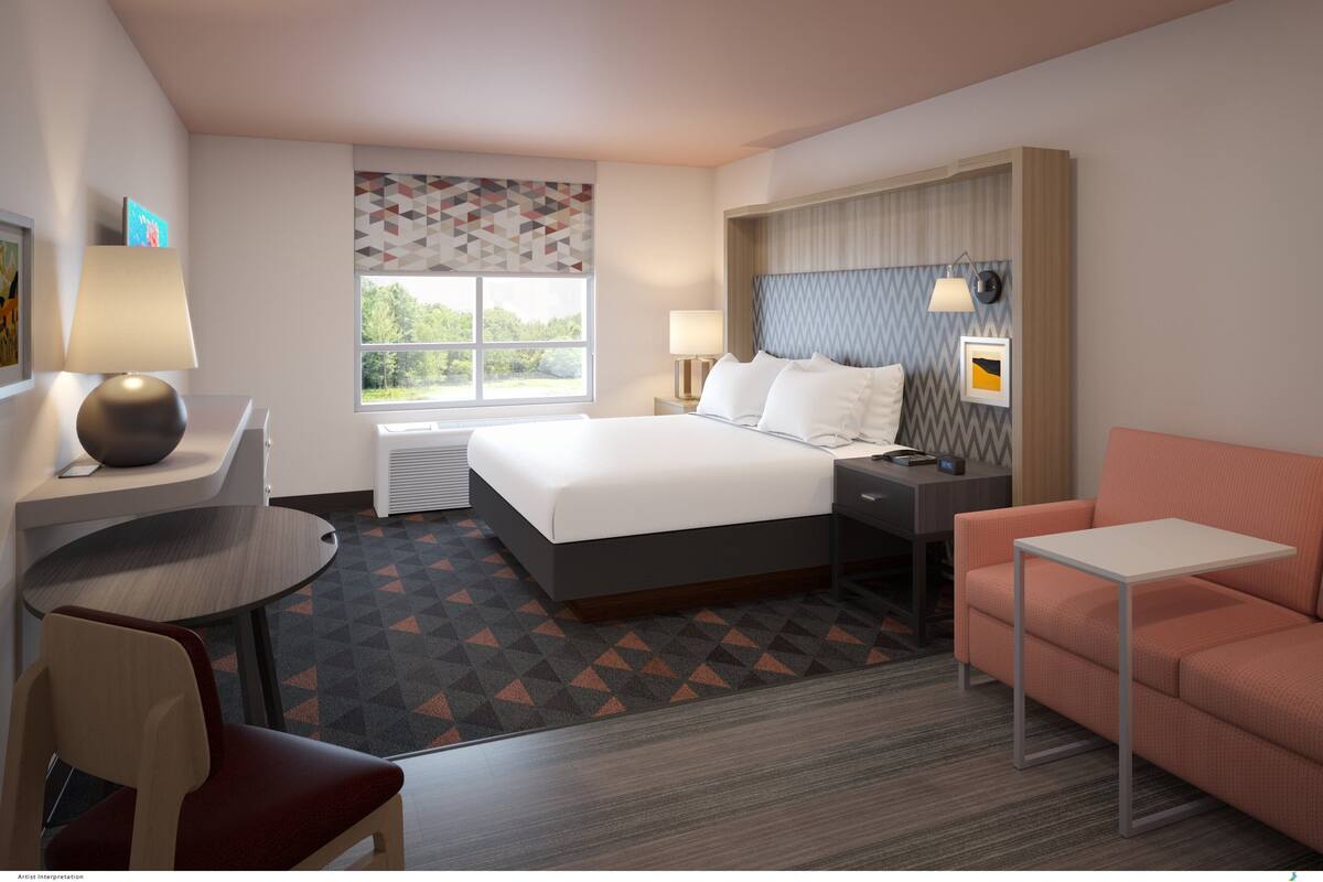 A hotel room with a bed, desk, chair, and a small table.
