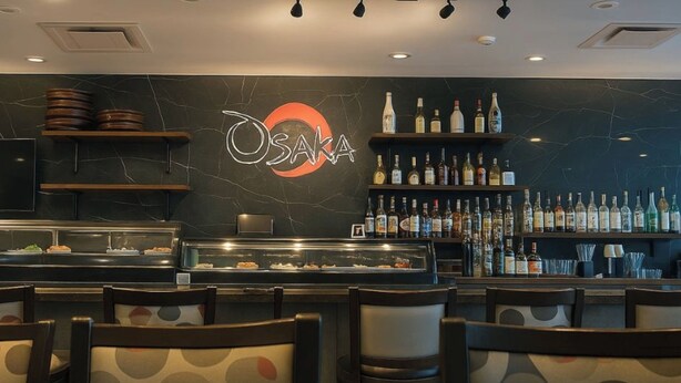 A bar area with a marble wall, shelves of liquor bottles, and a display case with pastries. - Holiday Inn Lexington - Hamburg by IHG (Lexington)