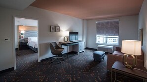 A hotel room with a bed, desk, chair, and a window with a view of buildings. - Holiday Inn Lexington - Hamburg by IHG (Lexington)