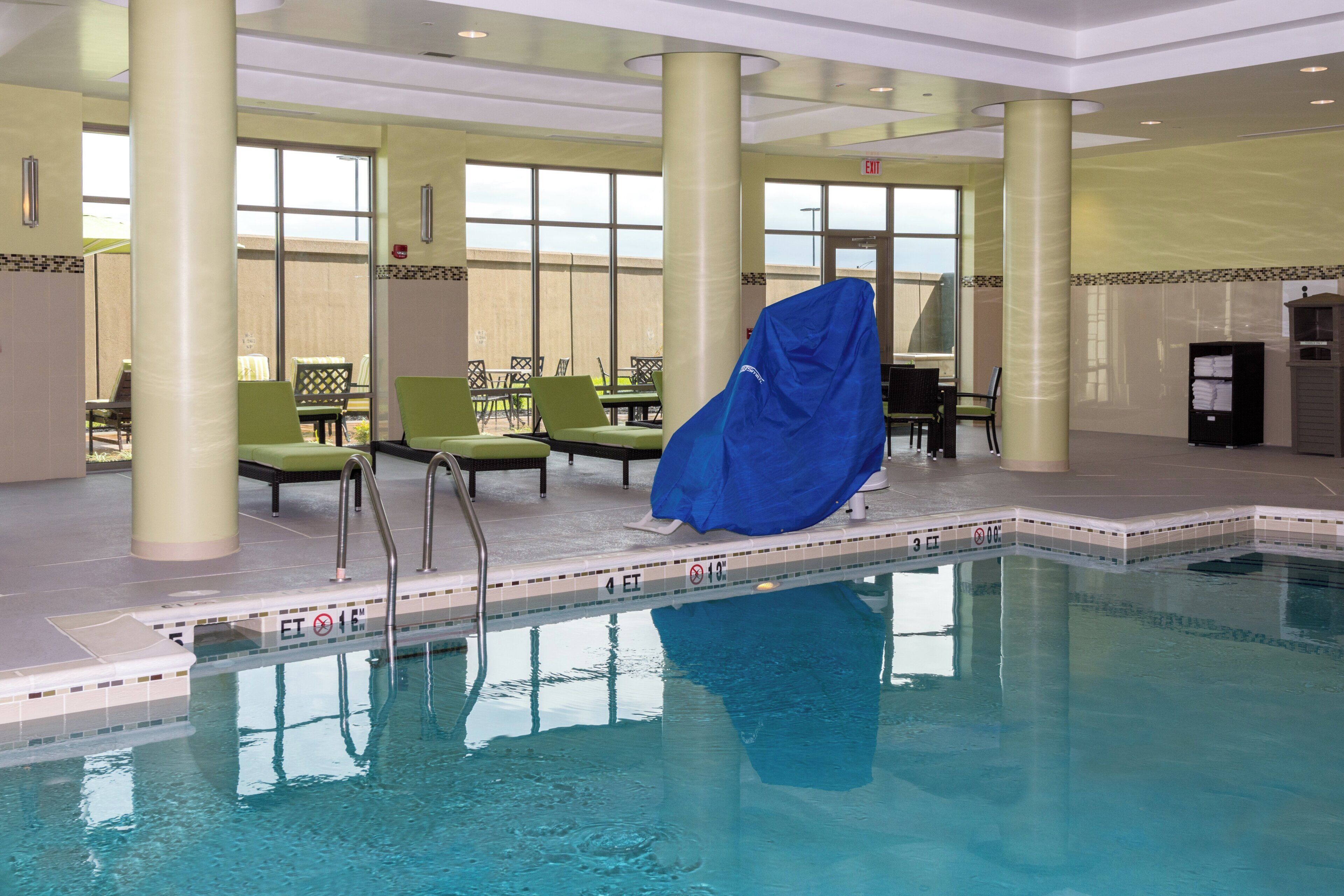 Una piscina interior con agua cristalina, rodeada de sillones de descanso y una zona de estar cubierta.