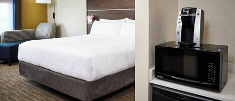 A hotel room with a bed, a microwave, a coffee maker, a chair, and a lamp.