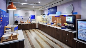 A breakfast area with a counter, a display of breakfast items, and a sign indicating the start of breakfast. - Holiday Inn Express and Suites Brantford by IHG (Brantford)
