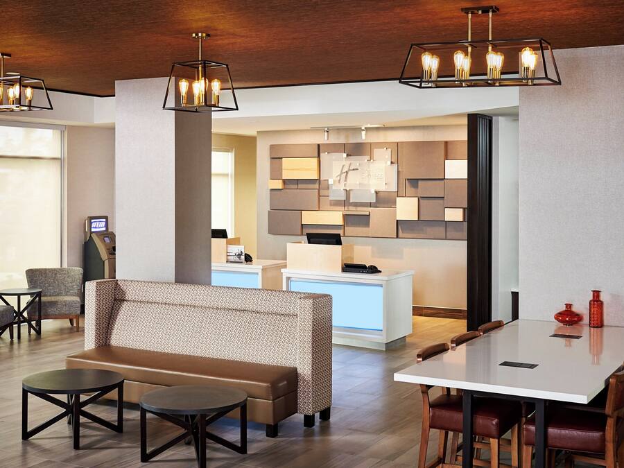 A hotel lobby with seating, a reception desk, and a modern light fixture.