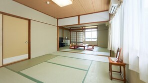 A traditional Japanese room with tatami flooring, a sliding door, a television, and a futon bed. - Ohamaso (Toba)