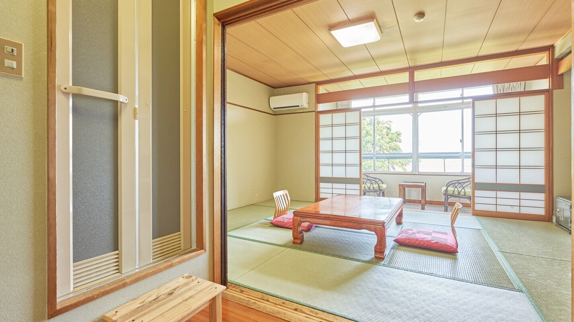 Una habitación japonesa tradicional con suelo de tatami, una mesa de madera y puertas correderas.