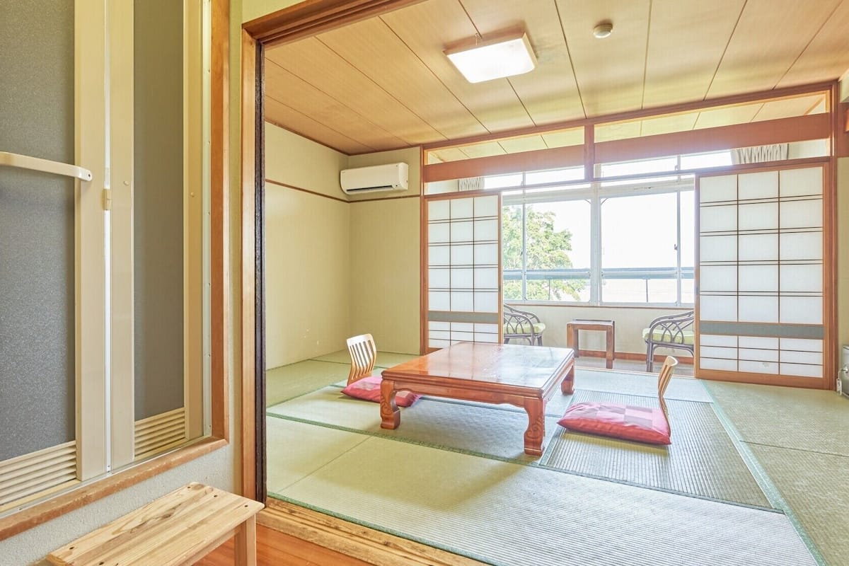 Une pièce de style japonais traditionnel, avec un sol recouvert de tatamis, une table en bois et des portes coulissantes.