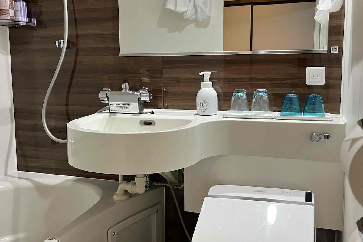 Une salle de bain avec un lavabo blanc, un miroir, un porte-serviettes et des toilettes.