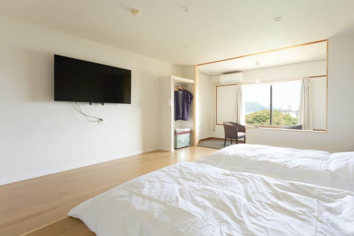 Une chambre d’hôtel équipée d’un lit, d’un téléviseur fixé au mur, d’une fenêtre avec vue et d’un bureau avec une chaise.