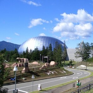 A modern building with a dome structure, surrounded by a landscaped area with rocks and trees. - Hokuriku Awara Onsen Matsuya Sen Sen (Awara)