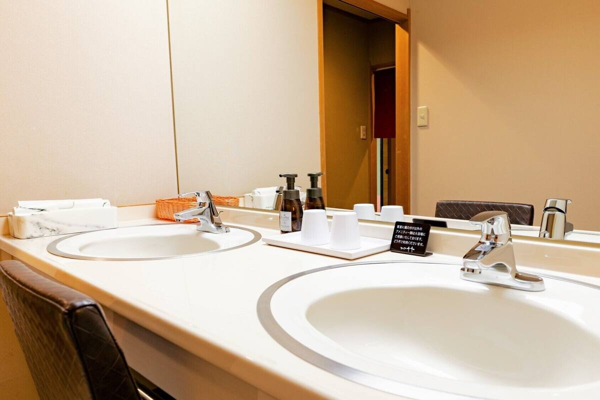 A hotel bathroom with two sinks, a mirror, and toiletries.