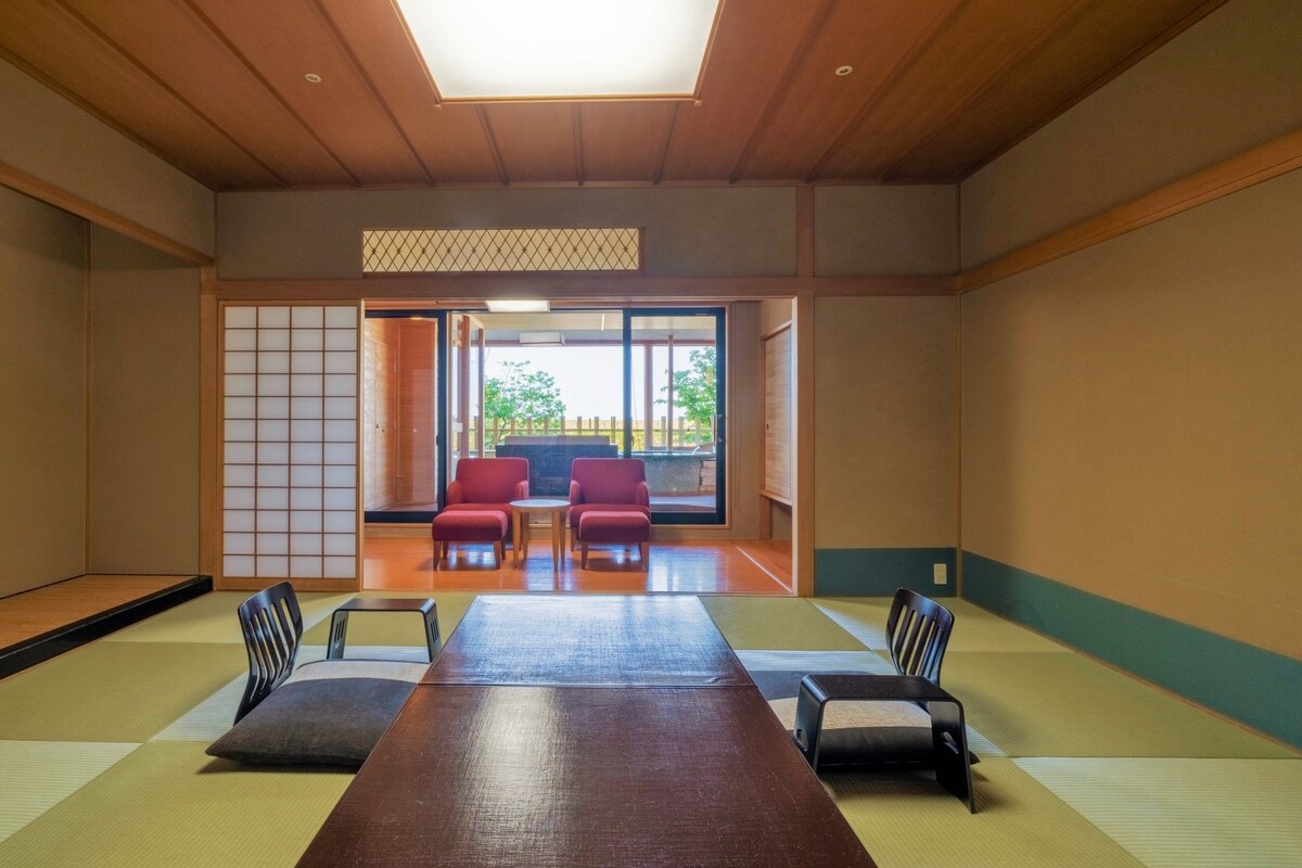 Une pièce de style japonais traditionnel, avec un sol recouvert de tatamis, une table basse et des chaises rouges.
