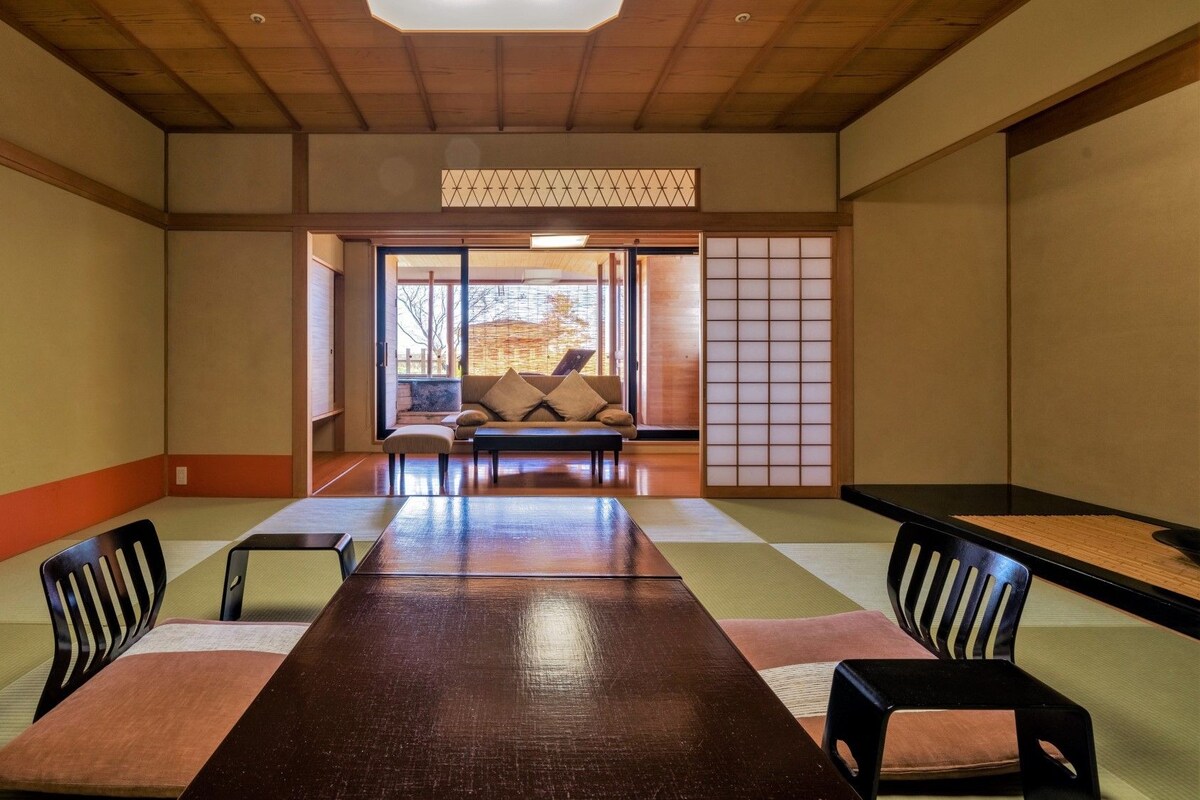 Una habitación tradicional japonesa con suelo de tatami, una mesa baja y un sofá.