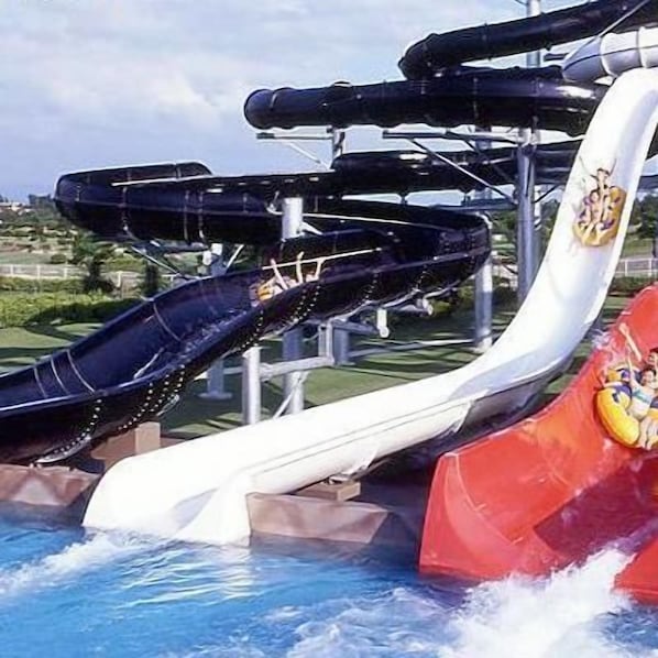 Un toboggan aquatique à plusieurs pistes, avec une section rouge et une personne au bas du toboggan.