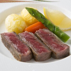 Un plato con carne en rodajas, verduras y un gajo de limón.