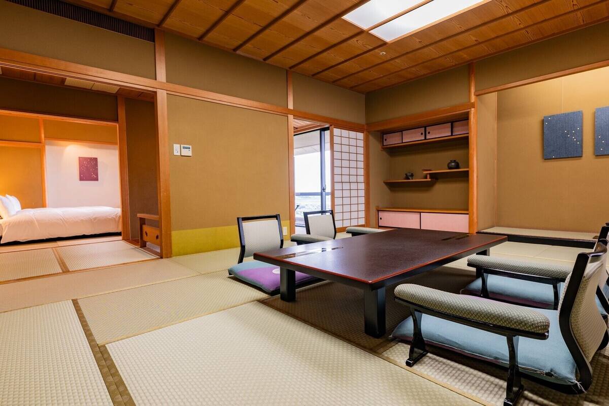 A traditional Japanese-style room with tatami flooring, a low table, and seating.