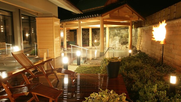 A wooden deck with chairs, a stone wall, and a fire feature.