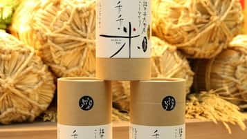 Three cylindrical containers with Japanese text, placed on a wooden surface with straw balls in the background.