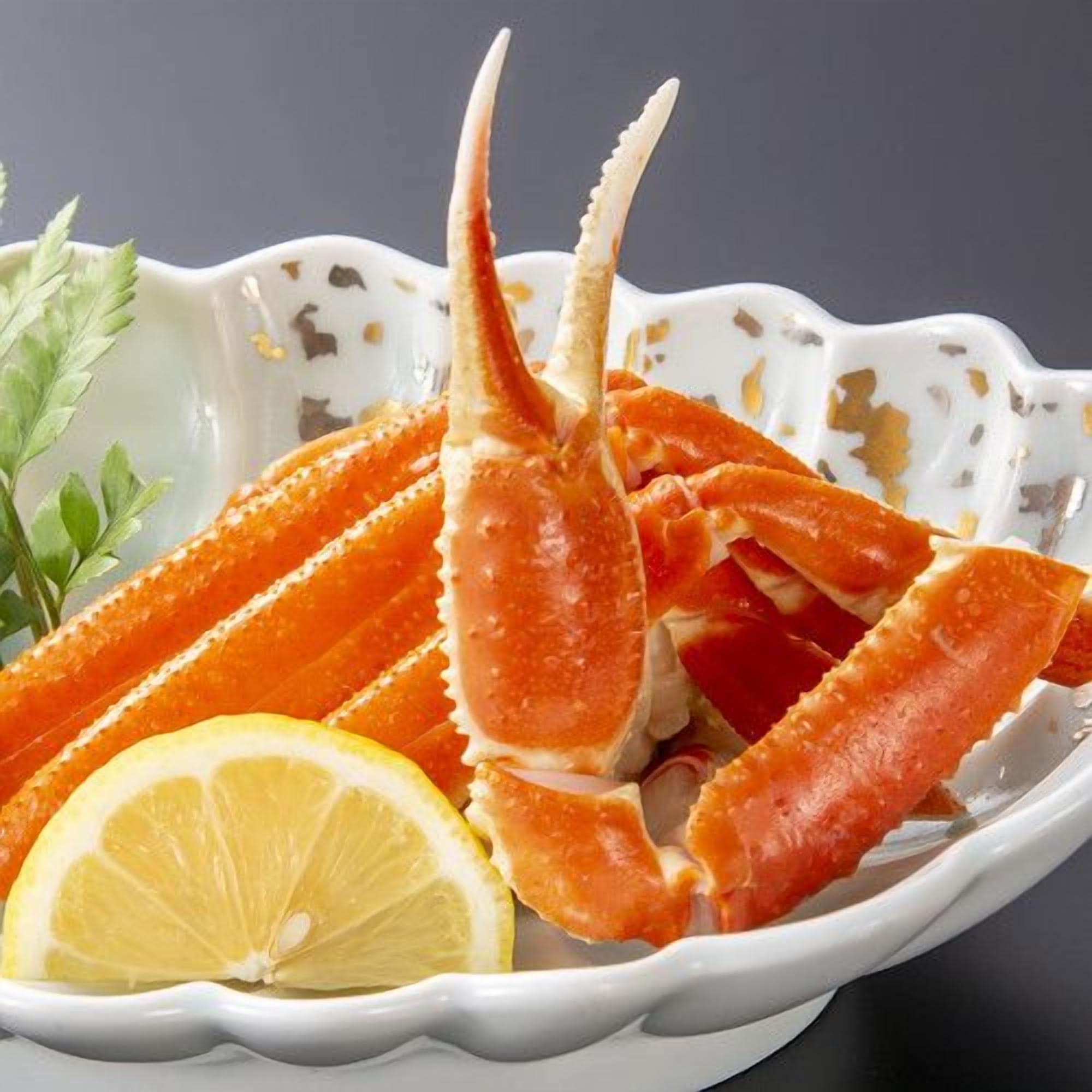 A bowl of crab legs with lemon and parsley garnish.