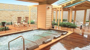 A spa area with a hot tub, wooden deck, and lounge chairs.
