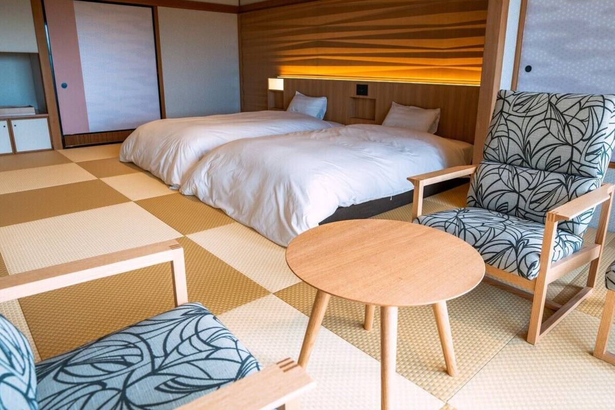 A hotel room with a bed, two chairs, a small table, and a wardrobe.