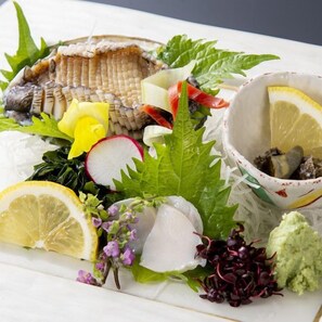 Un piatto di pesce con diversi contorni e una ciotola di salsa.