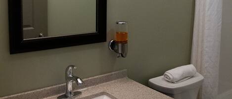 A bathroom with a sink, mirror, towel rack, and toilet.