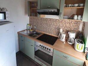 A kitchen with a microwave, sink, stove, and various kitchen utensils. - 2-Room Vacation Rental - Turteltäubchen Vacation Apartments and Rooms (Binz)
