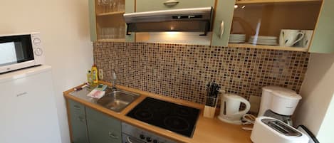 Una cocina compacta equipada con microondas, estufa, fregadero y cafetera.