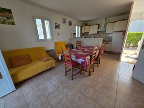 A compact living space with a sofa, dining table, chairs, and a kitchen area.
