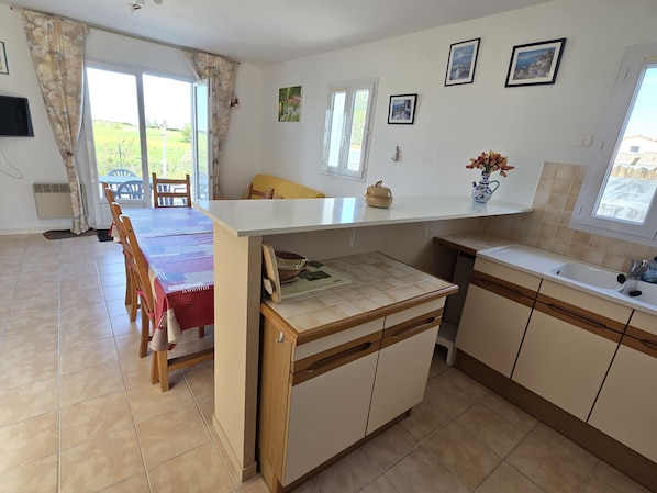 A kitchen with a dining area, a window with a view, and a small sink.
