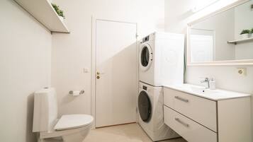 A compact, modern bathroom with a toilet, washing machine, and sink.