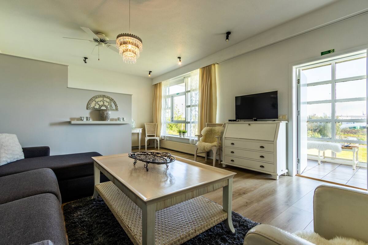 Una sala de estar moderna con un sofá, una mesa de centro, un televisor y un ventanal con cortinas.