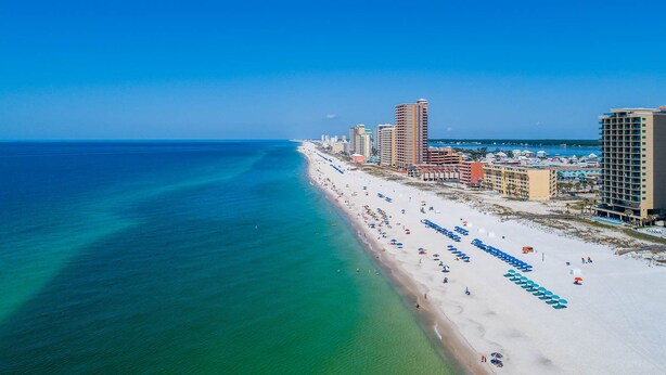 A coastal cityscape with a wide beach, high-rise hotels, and clear blue waters.