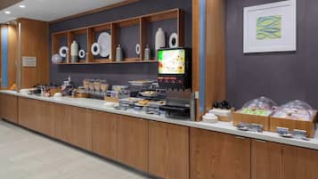 A buffet counter with various food items and a coffee machine.